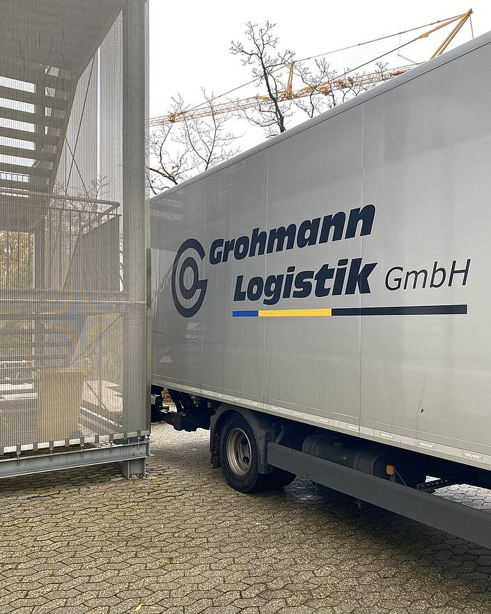 LKW an Gebäudeteil mit Außentreppe