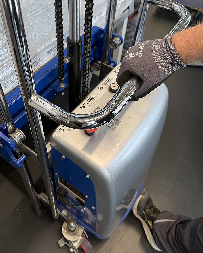 Detail eines elektrischen Hubwagens mit einer Hand des Bedieners.